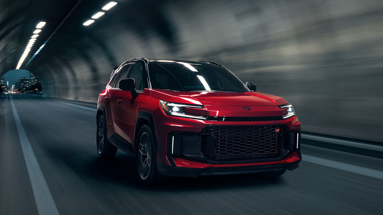 RAV4 Plug-in Hybrid GR Sport in Supersonic Red with Midnight Black Metallic roof driving through a dimly lit tunnel
