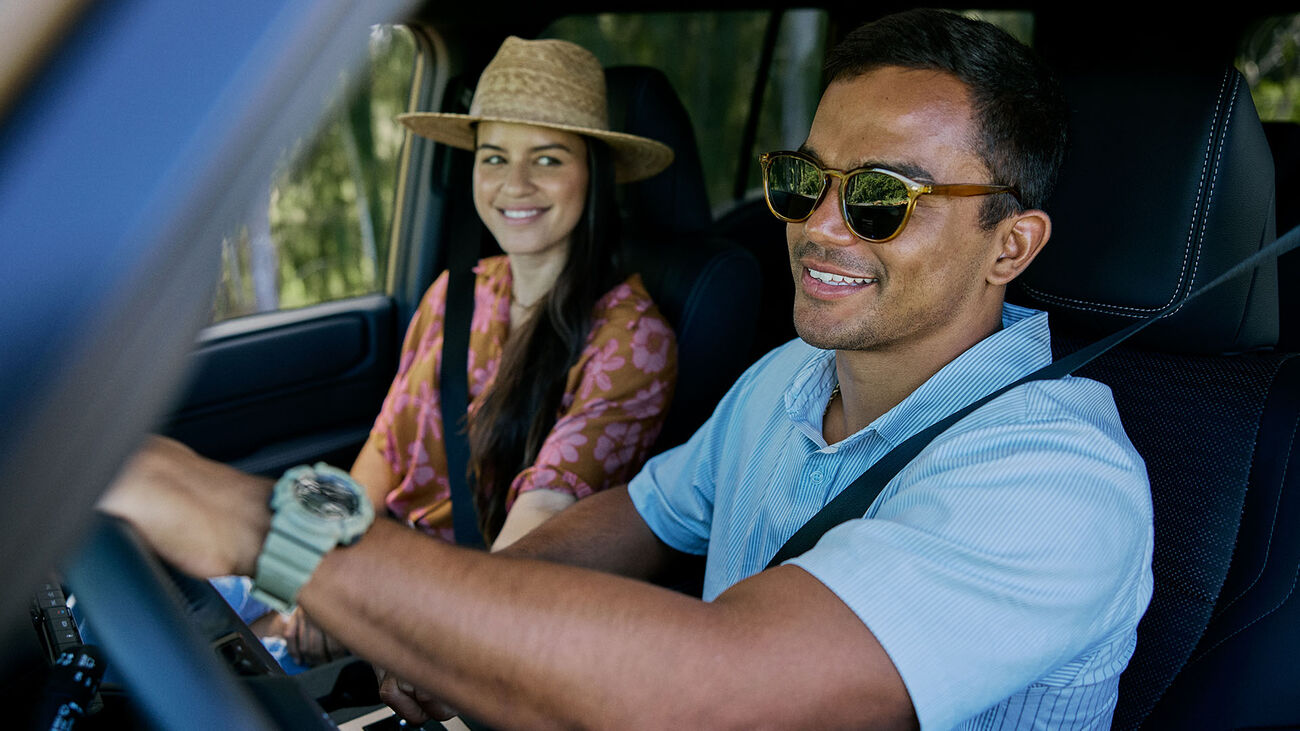 Toyota Land Cruiser in Trail Dust with a young couple in the cabin of the vehicle.