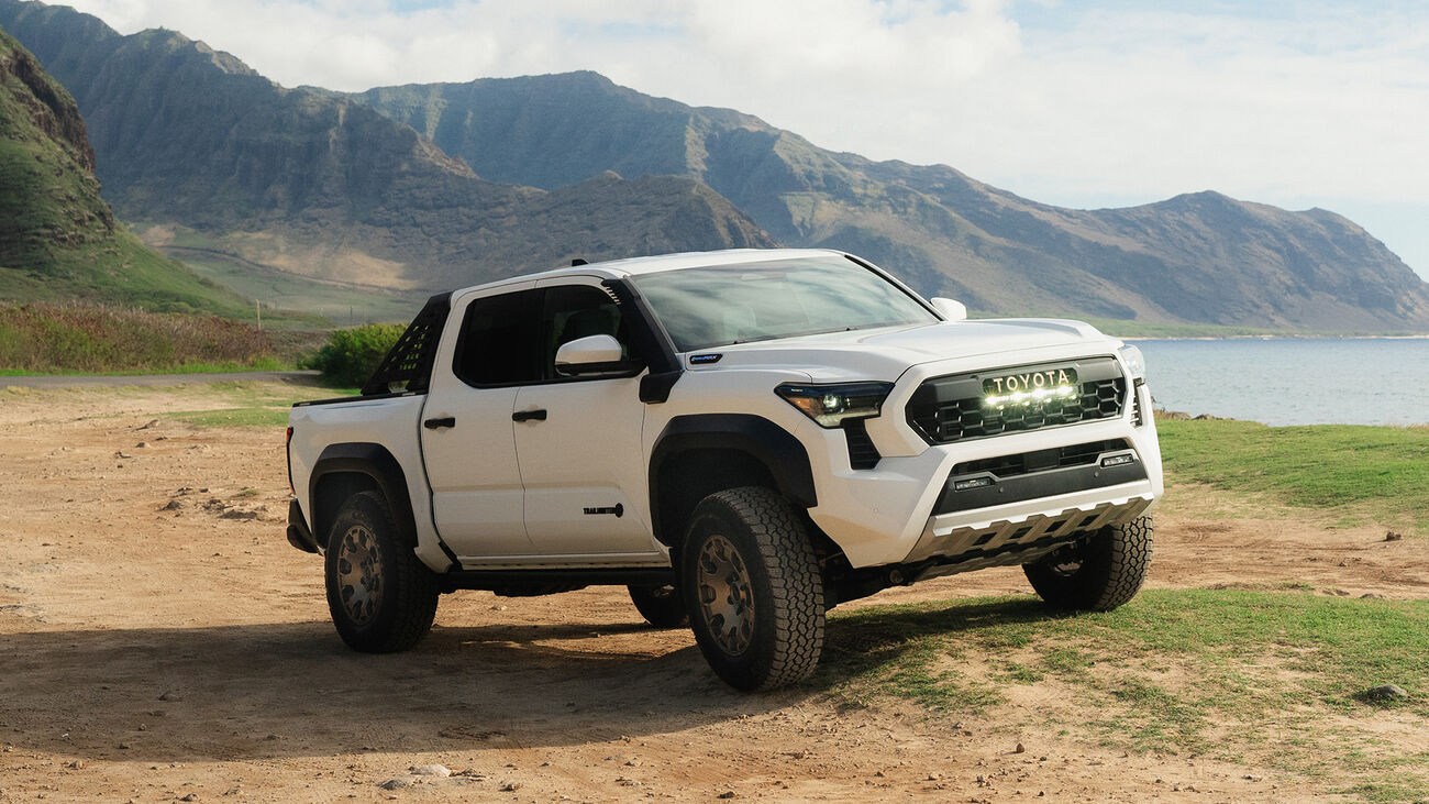 Toyota Tacoma i-FORCE MAX Trailhunter in Ice Cap traversing a rocky dirt road along side the ocean