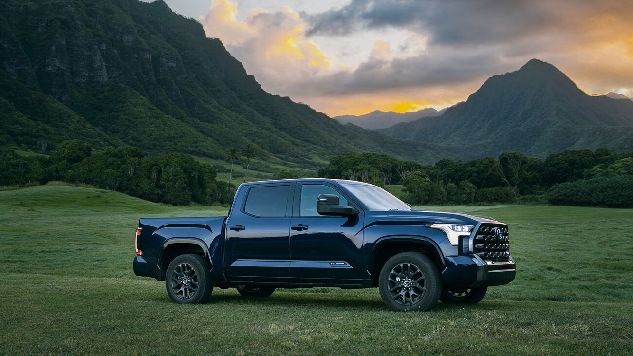  Toyota Tundra i-FORCE MAX Platinum in Blueprint staged in a grassy plain with tall mountains and stunning sunset in the background