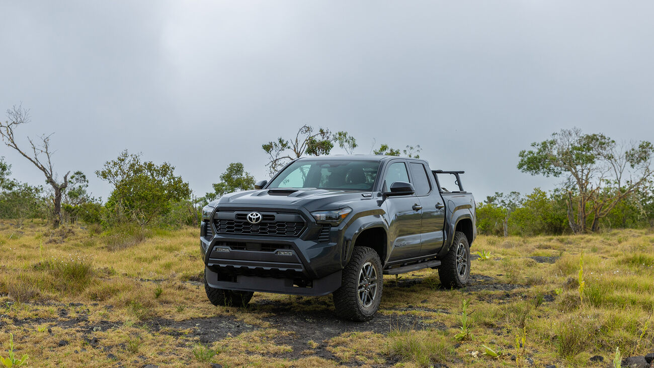 Toyota Tacoma i-FORCE MAX TRD Sport in Underground staged in a grass and gravel field in front of greenery.