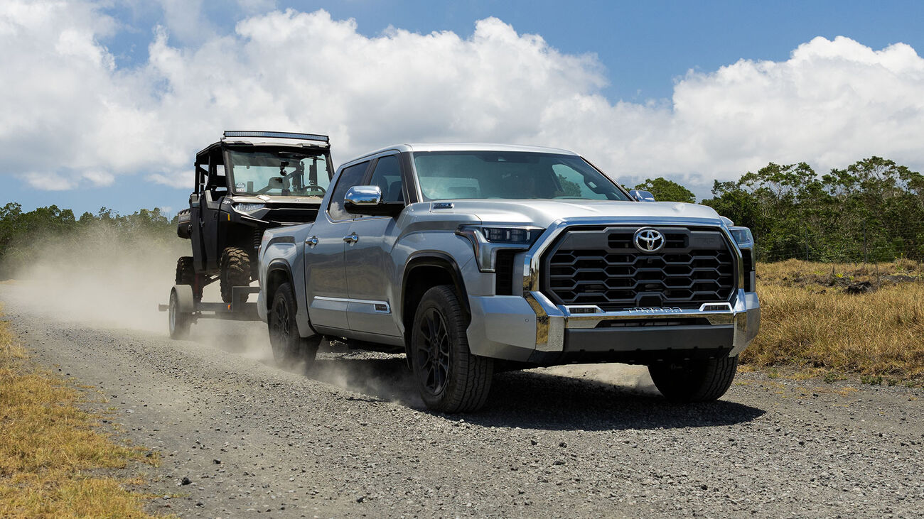 2026 Tundra i-FORCE MAX driving down a gravel road while towing a utility terrain vehicle.