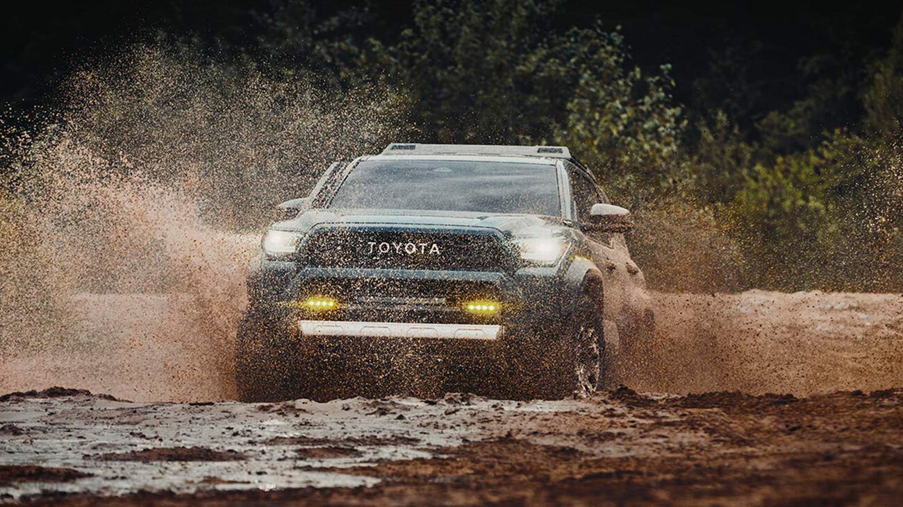Toyota 4Runner i-FORCE MAX Trailhunter in Everest driving through a mud puddle splashing water higher than the vehicle.