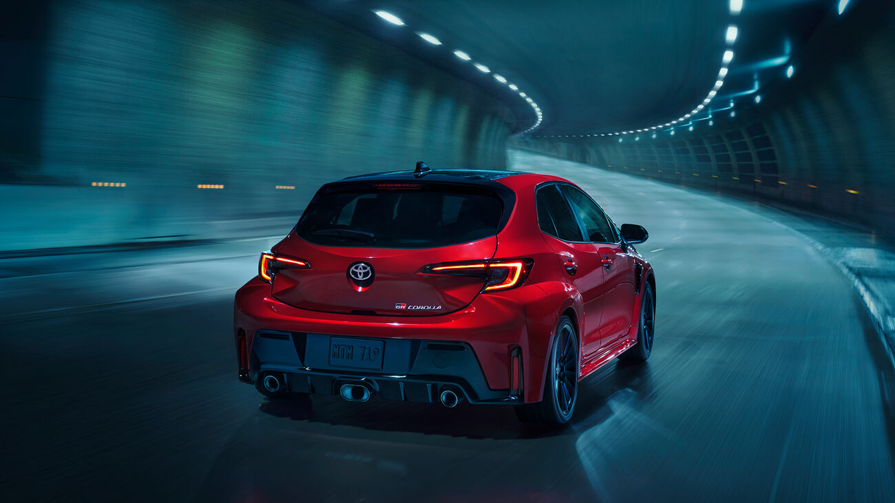 GR Corolla in Supersonic Red driving away on a curving tunnel road