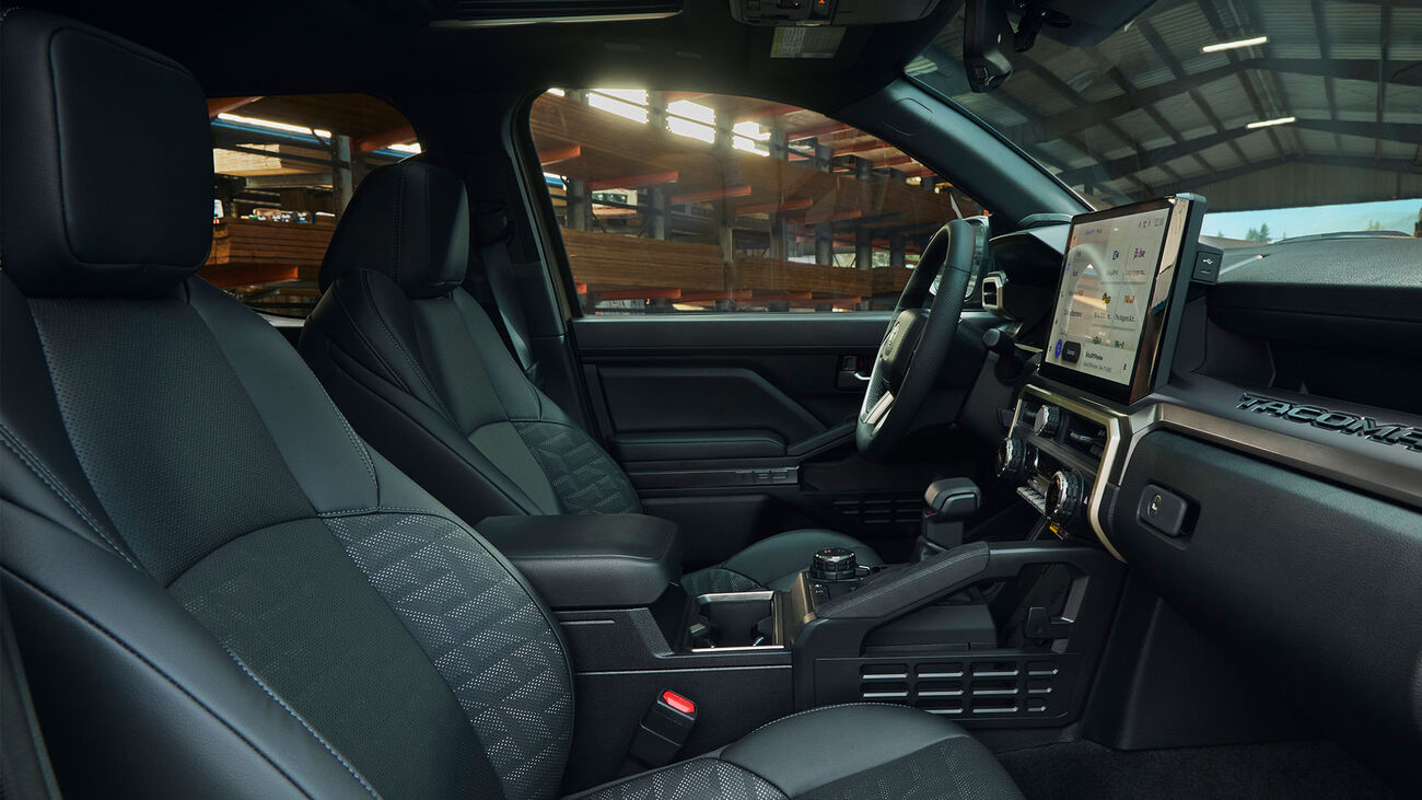 Toyota Tacoma i-FORCE MAX TRS Sport&rsquo;s interior with the available Black SofTex&reg; trim while parked in a warehouse