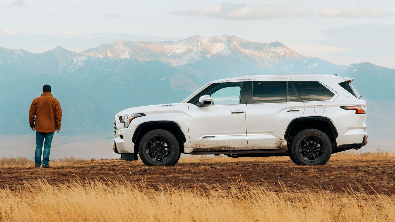 Toyota Sequoia 1794 Edition with TRD Off-Road Package in Wind Chill Pearl parked at a scenic location with dried out tall grass in front and snowy mountains in the background. 