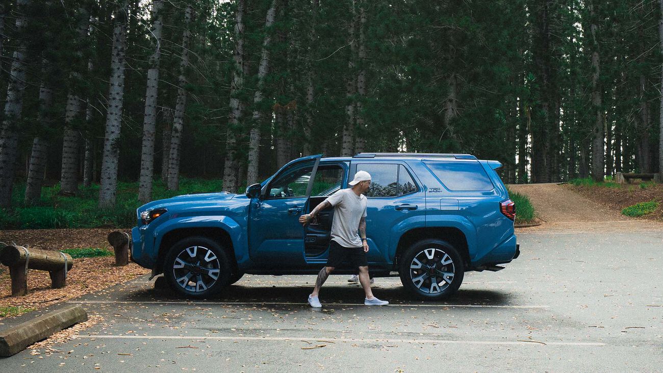 The 2026 Toyota 4Runner TRD Sport parked in a forest parking lot with the male driver exiting the vehicle.