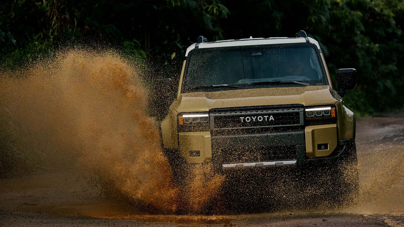 2026 Toyota Land Cruiser speeding through a mud puddle splashing water as high as the height of the vehicle. 